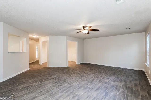 a view of an empty room with a chandelier fan and wooden floor