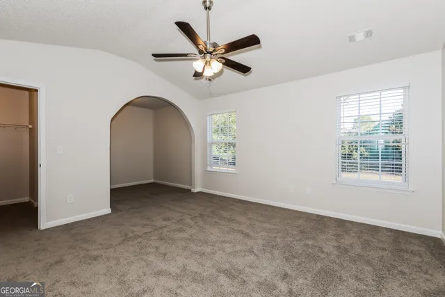an empty room with ceiling fan and window