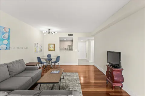 a living room with furniture a flat screen tv and kitchen view