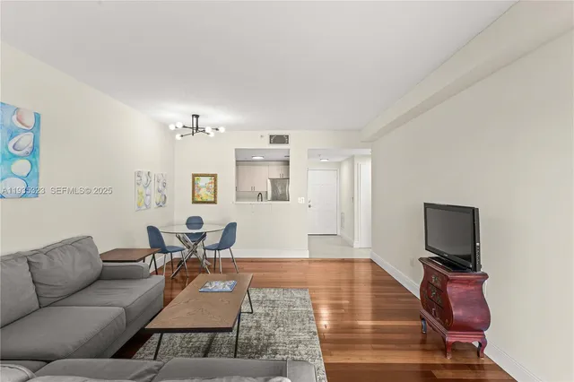 a living room with furniture a flat screen tv and kitchen view