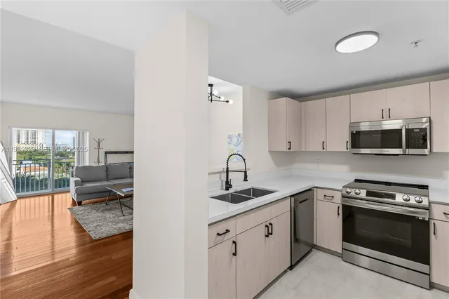 a kitchen with stainless steel appliances granite countertop a stove top oven a sink dishwasher and white cabinets with wooden floor