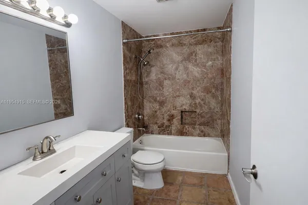 a bathroom with a bathtub shower sink vanity and toilet