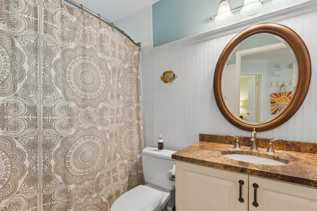 a bathroom with a granite countertop toilet a sink and a mirror