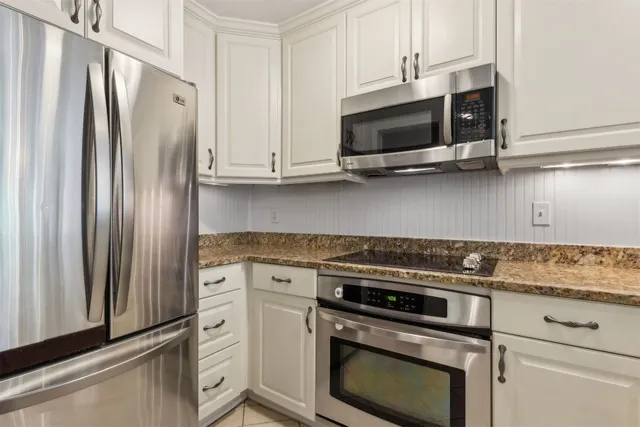 a kitchen with stainless steel appliances white cabinets and a stove a refrigerator with wooden floors