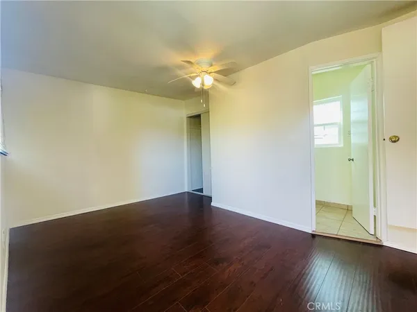 an empty room with wooden floor and fan
