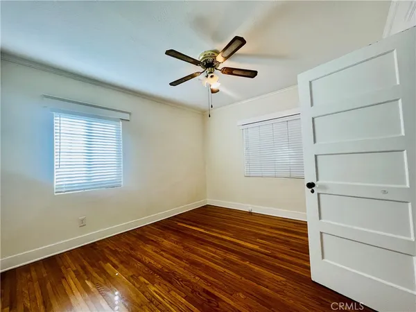 a view of an empty room with a window and wooden floor