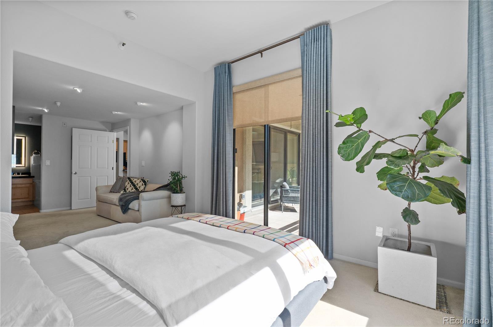 180 Cook Street, Unit 203 Denver, CO 80206 - Photo 21 of 44 a bedroom with a balcony a bed and a potted plant