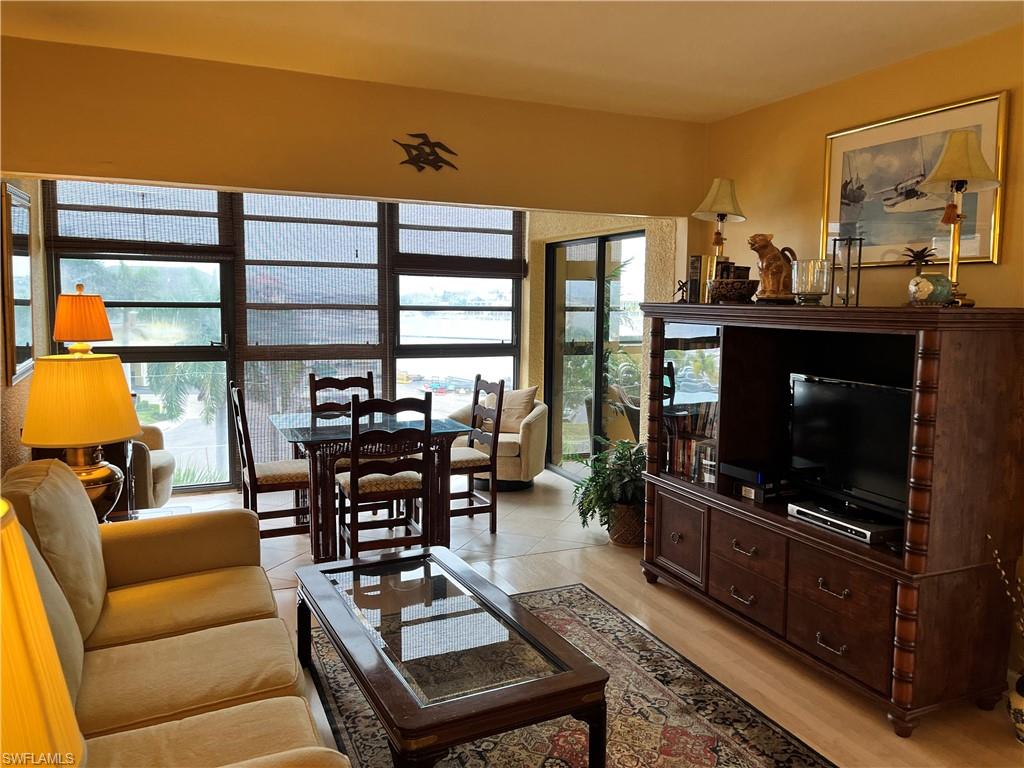 807 River Point Drive, Unit 304D Naples, FL 34102 - Photo 5 of 23 a living room with furniture a flat screen tv and a floor to ceiling window