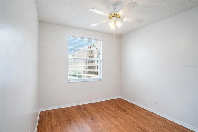 an empty room with a window and a ceiling fan