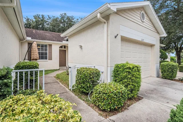 a view of a house with a small yard plants and large trees