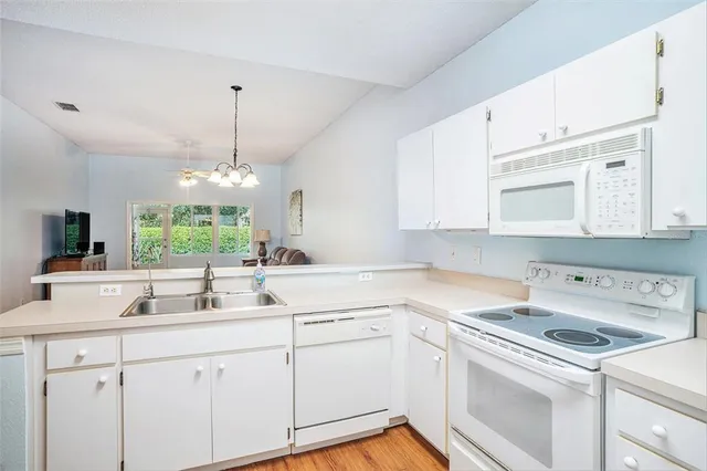 a kitchen with a sink dishwasher and white cabinets with wooden floor