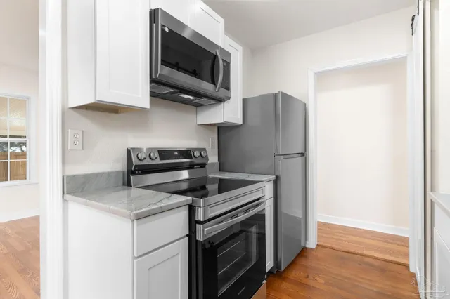 a kitchen with stainless steel appliances granite countertop white cabinets and a granite counter top