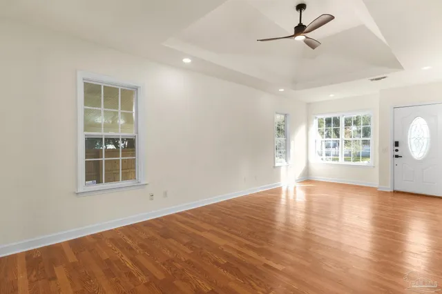 a view of an empty room with a window and wooden floor