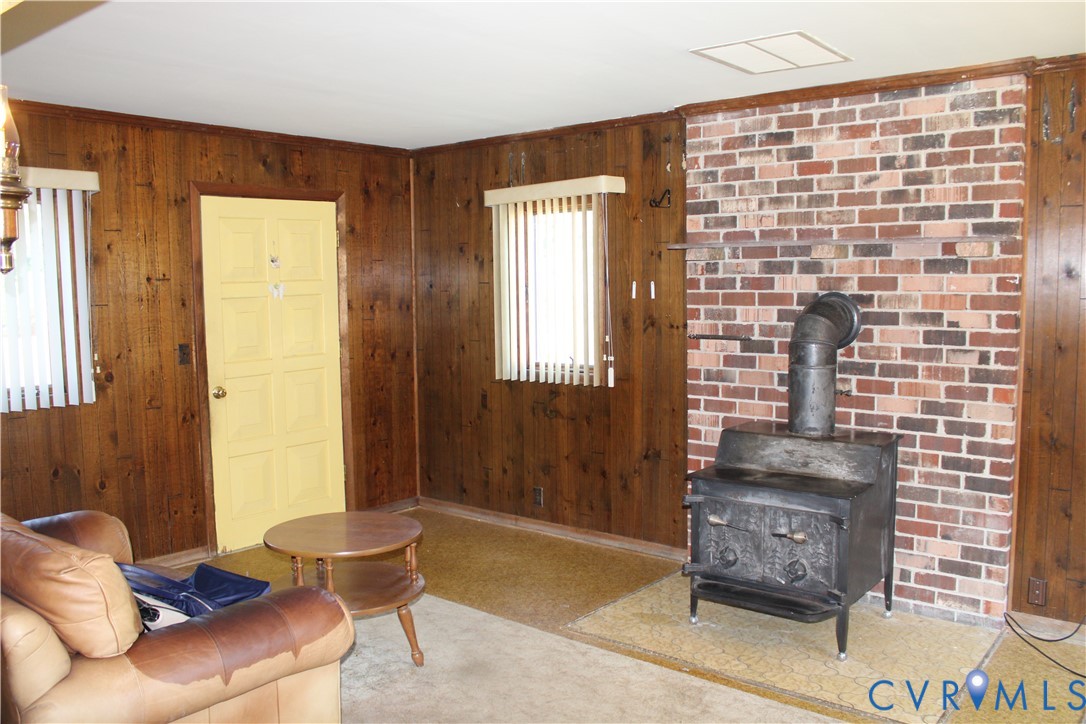 6221 Sturgeon Point Road Providence Forge, VA 23140 - Photo 7 of 26 Wood-paneled walls, brick accent wall, wood-burnin