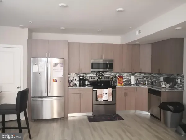 a kitchen with stainless steel appliances a refrigerator a stove top oven a sink dishwasher and white cabinets with wooden floor