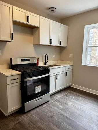 a kitchen with stainless steel appliances a stove a sink and white cabinets