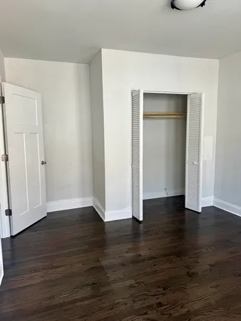 a view of an empty room with wooden floor and closet