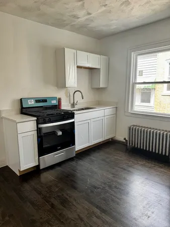 a kitchen with stainless steel appliances a stove a sink and white cabinets
