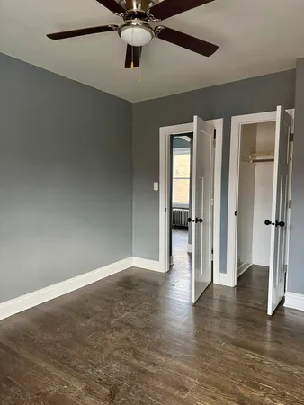 an empty room with wooden floor fan and windows