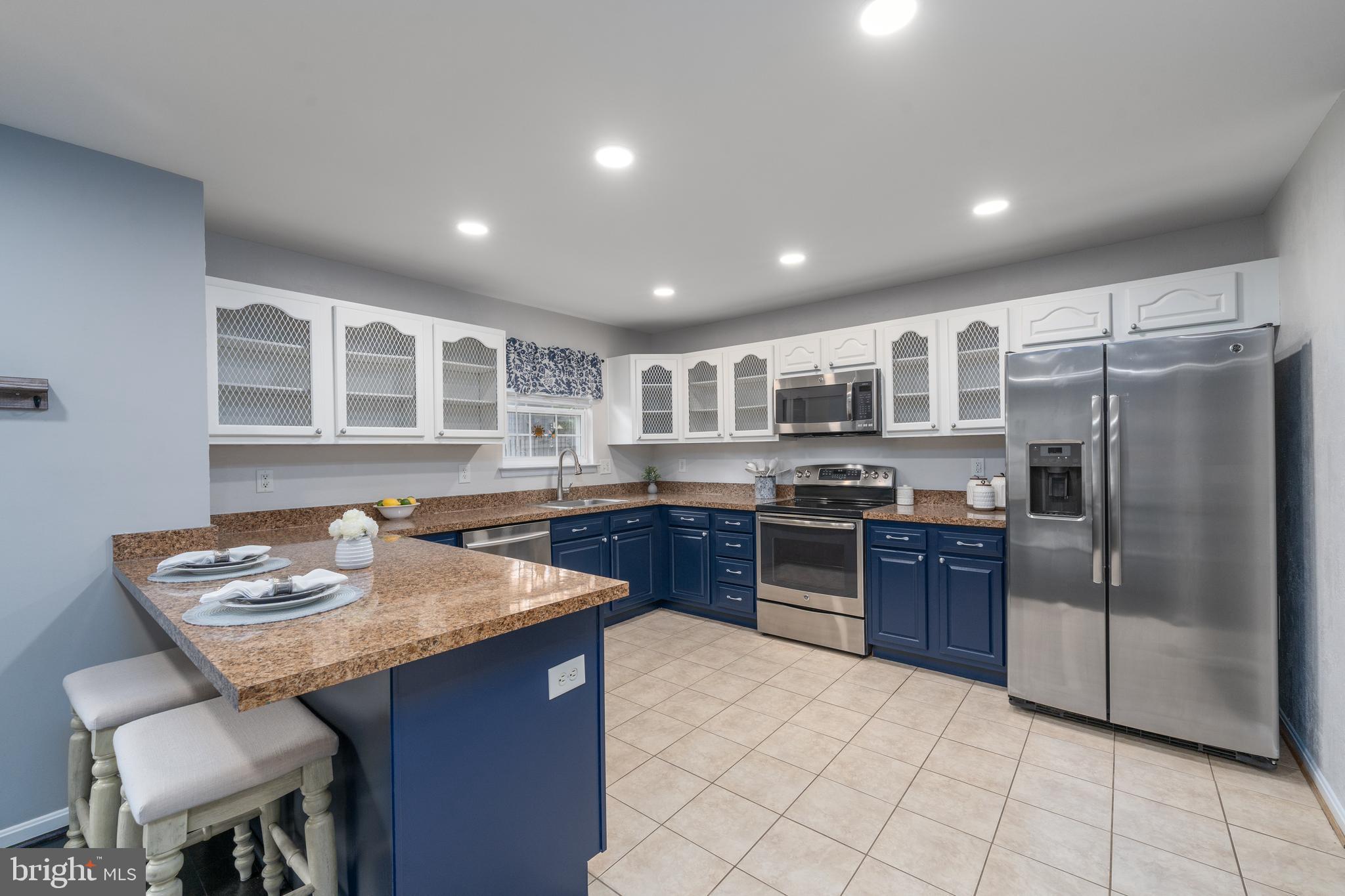 7815 Outing Avenue Pasadena, MD 21122 - Photo 9 of 37 a kitchen with stainless steel appliances granite countertop a stove a sink a refrigerator dining table and chairs