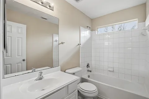 a bathroom with a bathtub shower sink mirror vanity and toilet