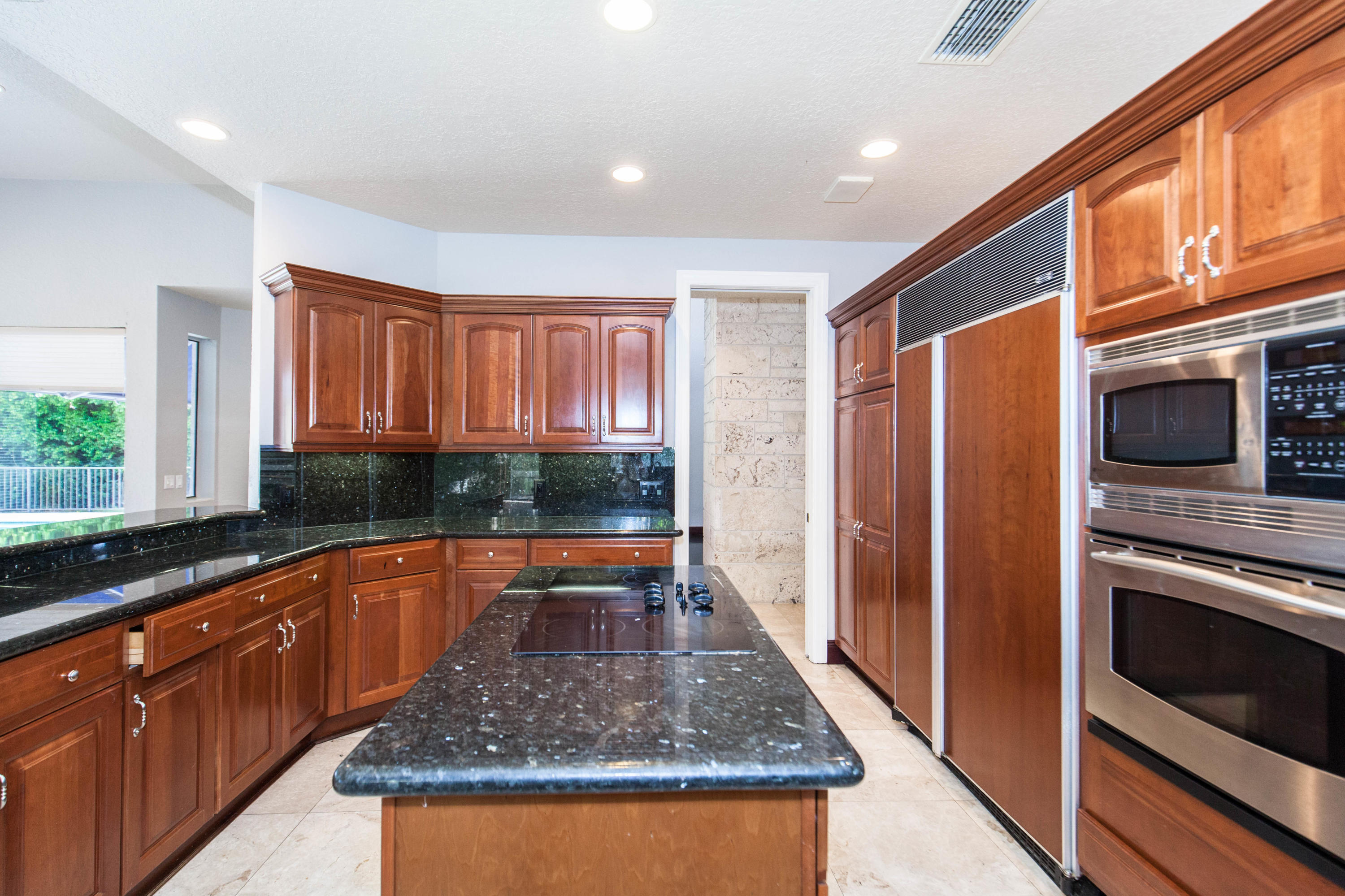 6087 Northwest 23rd Terrace Boca Raton, FL 33496 - Photo 15 of 64 a kitchen with stainless steel appliances granite countertop a refrigerator a stove and a sink with wooden cabinets