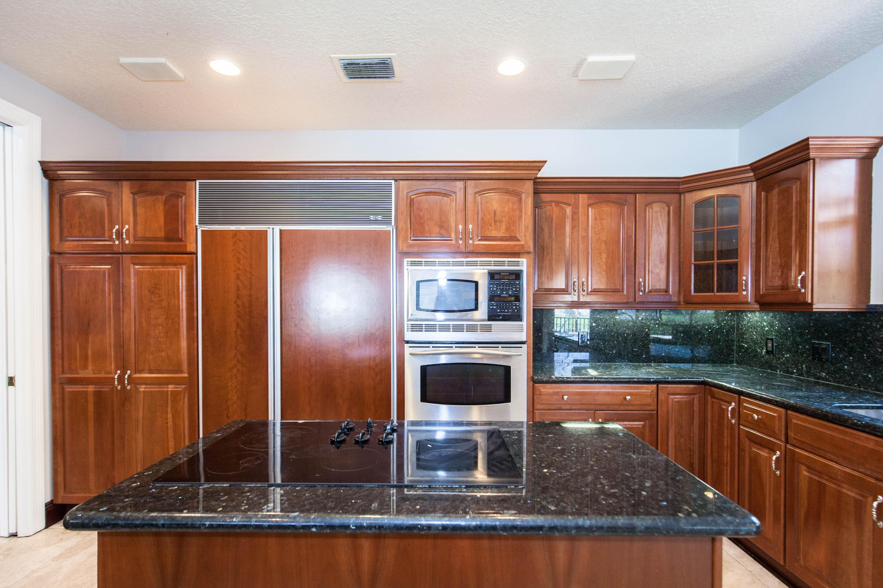 6087 Northwest 23rd Terrace Boca Raton, FL 33496 - Photo 16 of 64 a kitchen with stainless steel appliances granite countertop a refrigerator a stove and a sink with wooden cabinets