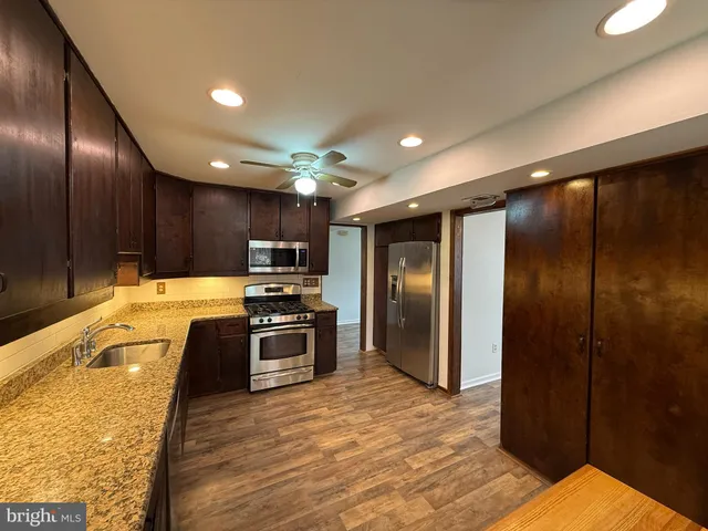 a large kitchen with stainless steel appliances kitchen island granite countertop a refrigerator and a sink