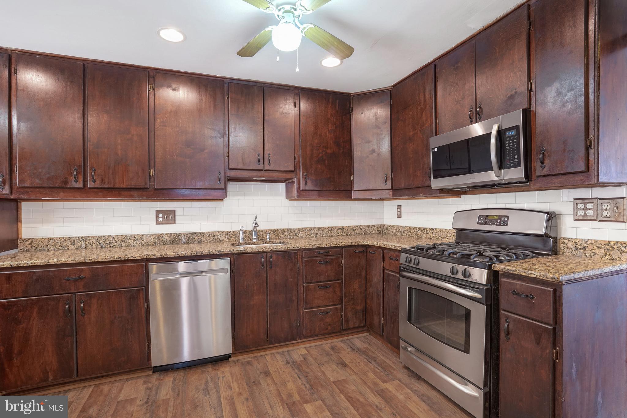 6710 Red Jacket Road Springfield, VA 22152 - Photo 13 of 53 a kitchen with stainless steel appliances granite countertop wooden cabinets a stove top oven a sink and dishwasher