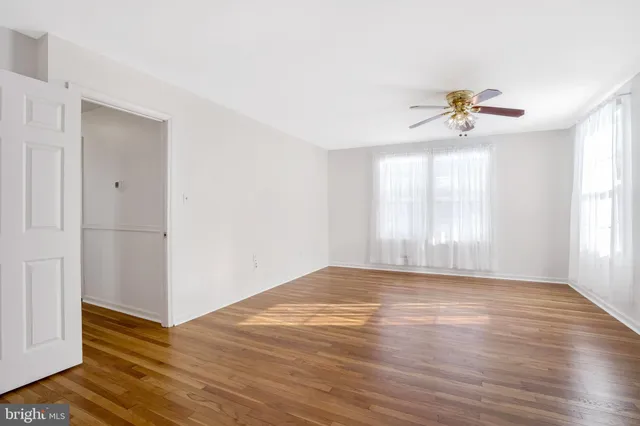 a view of an empty room with window and wooden floor