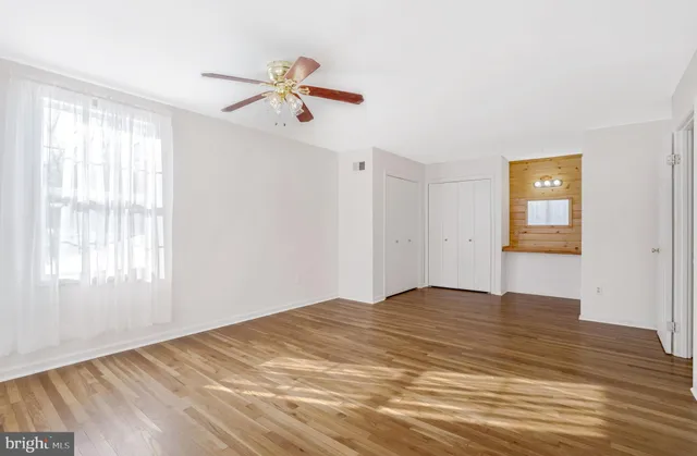 a view of empty room with wooden floor and fan