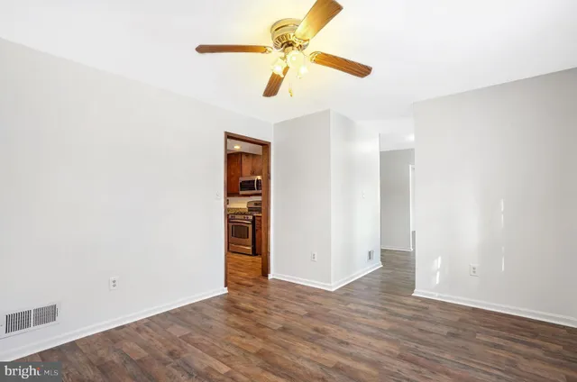 an empty room with wooden floor ceiling fan and window