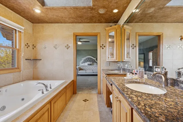 a bathroom with a granite countertop tub sink and mirror