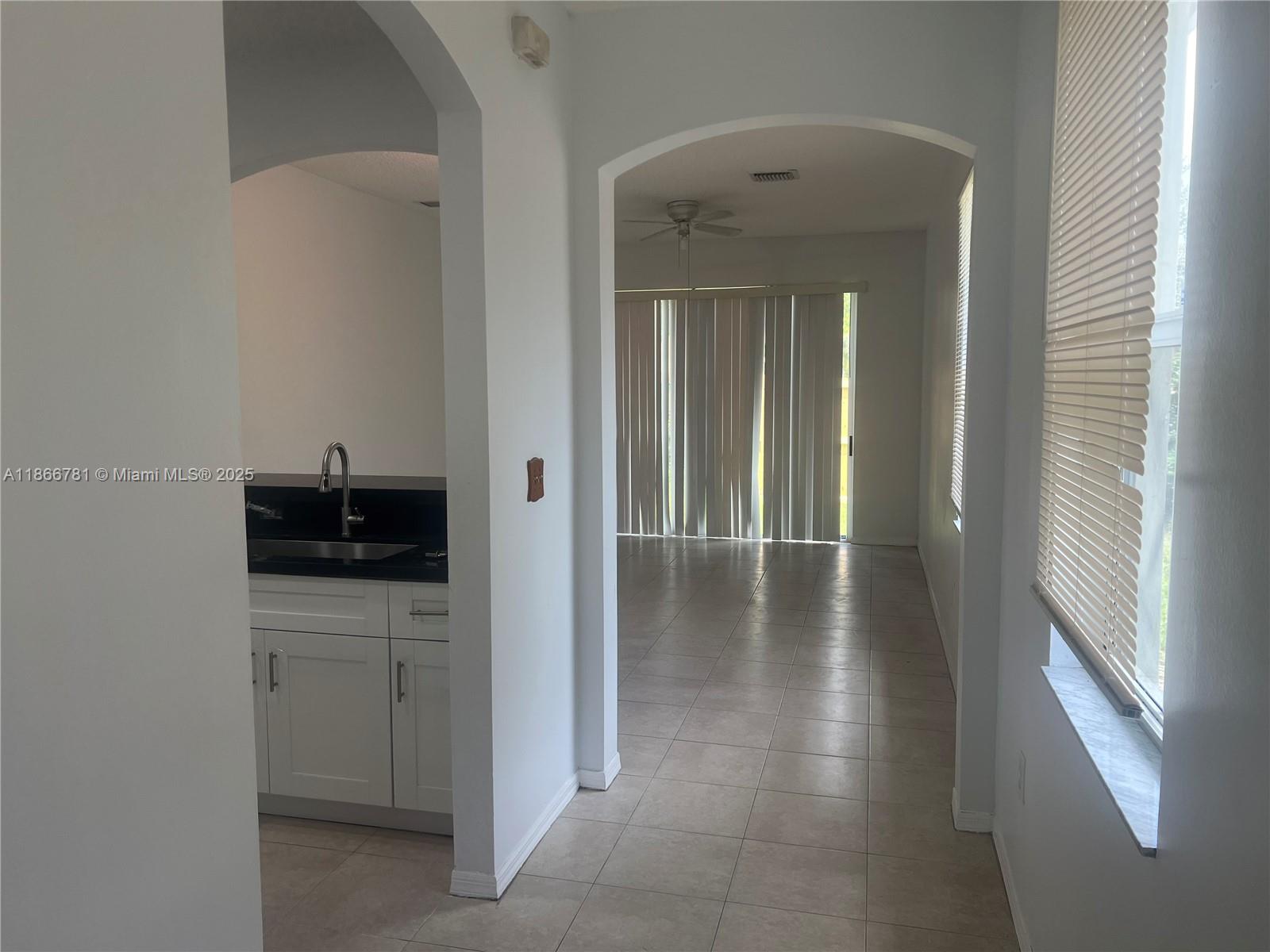4287 Northeast 9th Street Homestead, FL 33033 - Photo 5 of 25 a view of a hallway to a livingroom with wooden floor a sink and windows