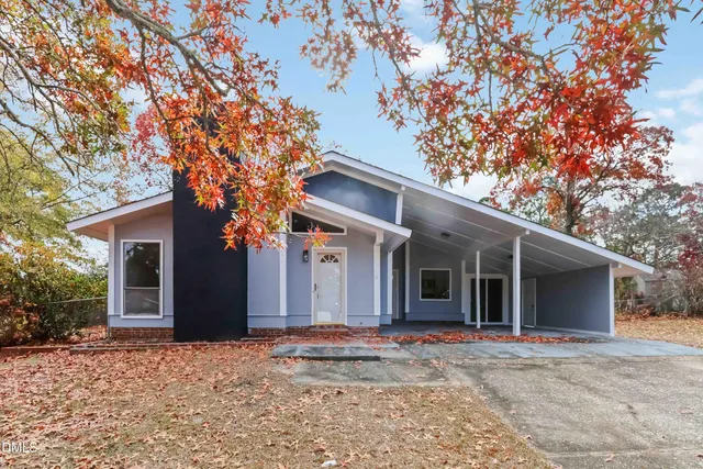 a view of a white house with a large tree