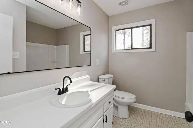 a bathroom with a toilet a sink and mirror