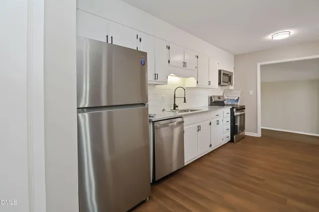 a kitchen with a sink a refrigerator and white cabinets