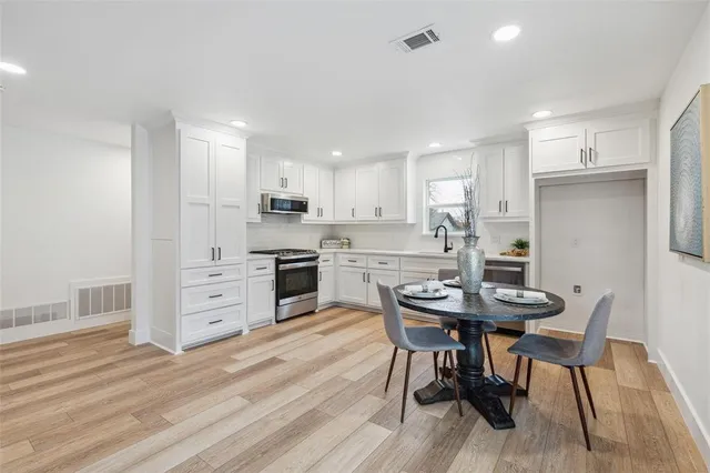 a kitchen with stainless steel appliances kitchen island granite countertop a table chairs and a refrigerator
