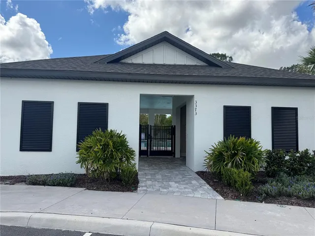 a view of a house with potted plants and a large tree