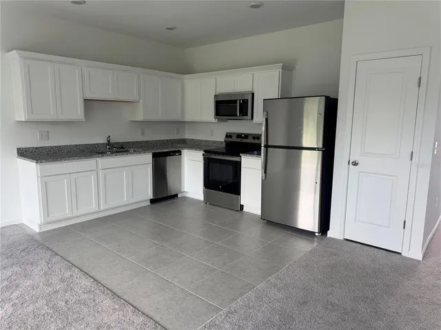 a kitchen with stainless steel appliances granite countertop a refrigerator sink and white cabinets