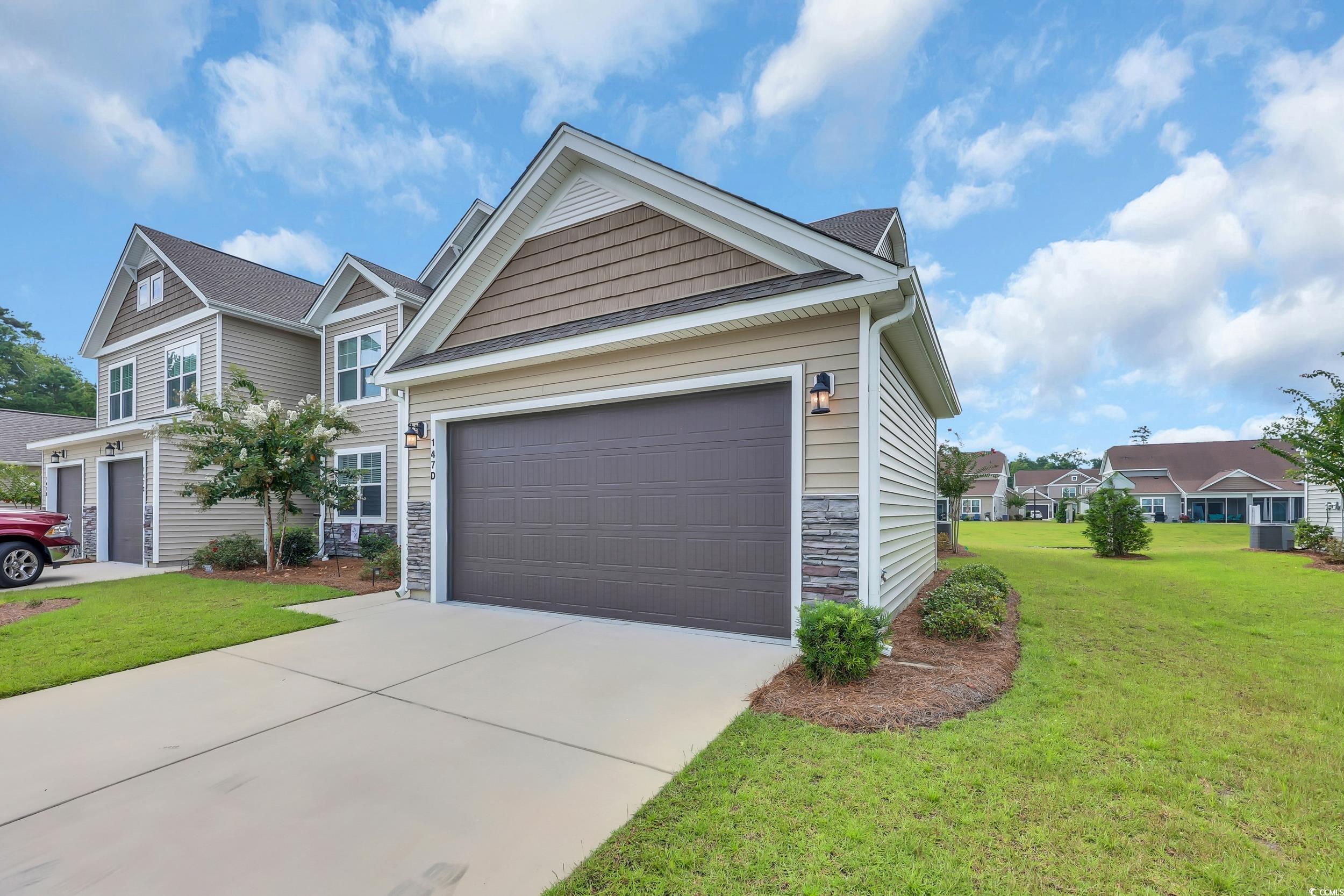 147 Machrie Loop, Unit D Myrtle Beach, SC 29588 - Photo 2 of 36 View of front of property featuring stone siding, a front lawn, and driveway