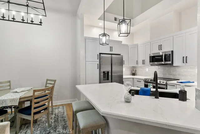 a kitchen with stainless steel appliances kitchen island granite countertop a table chairs microwave and refrigerator