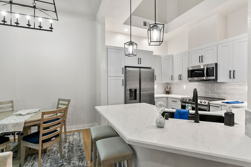 8 Coral Ridge, Unit 109 Laguna Niguel, CA 92677 - Photo 7 of 29 a kitchen with stainless steel appliances kitchen island granite countertop a table chairs microwave and refrigerator
