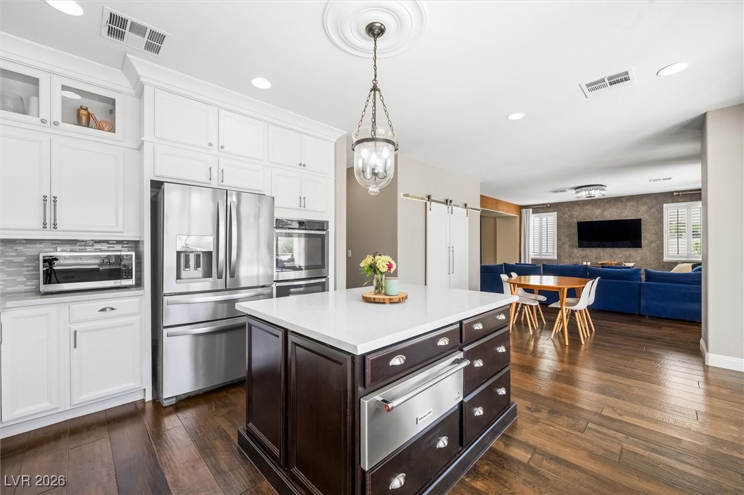 1673 Ravanusa Drive Henderson, NV 89052 - Photo 12 of 66 Kitchen featuring a barn door, appliances with stainless steel finishes, white cabinets, a warming drawer, and recessed lighting