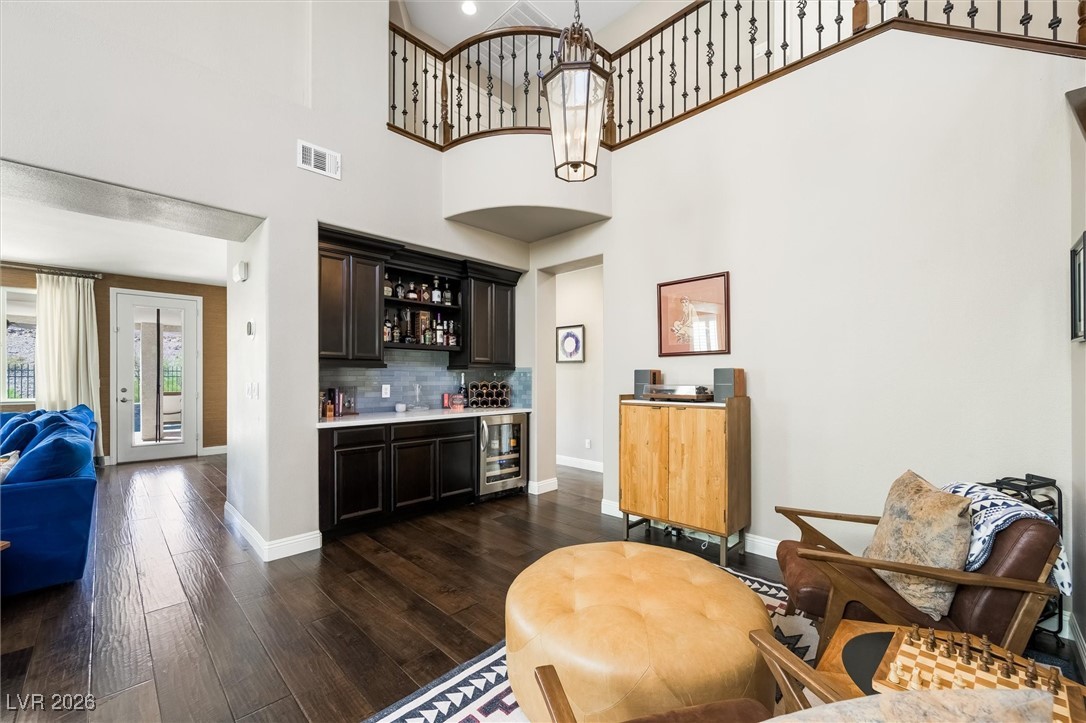 1673 Ravanusa Drive Henderson, NV 89052 - Photo 16 of 66 Indoor bar featuring light countertops, dark wood-style floors, tasteful backsplash, open shelves, and beverage cooler