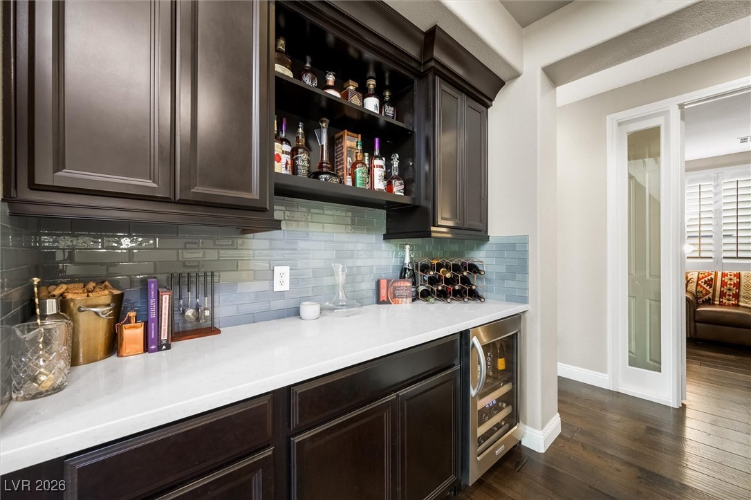 1673 Ravanusa Drive Henderson, NV 89052 - Photo 17 of 66 Indoor dry bar featuring open shelves, backsplash, beverage cooler, dark wood-type flooring, and dark brown cabinetry