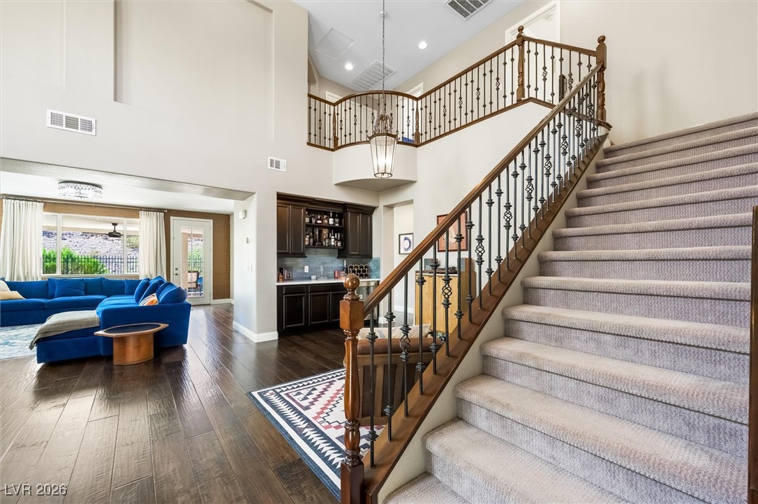 1673 Ravanusa Drive Henderson, NV 89052 - Photo 27 of 66 Stairs with wet bar, wood-type flooring, a towering ceiling, and recessed lighting