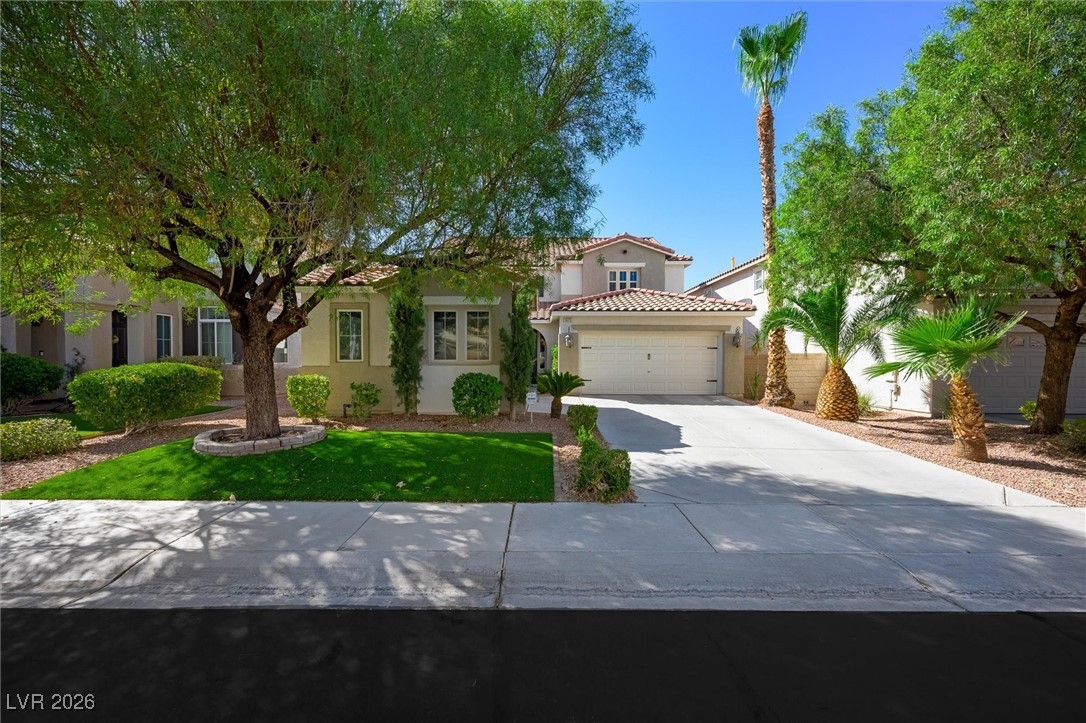 1673 Ravanusa Drive Henderson, NV 89052 - Photo 58 of 66 Mediterranean / spanish home featuring concrete driveway, stucco siding, a garage, a tile roof, and a front lawn