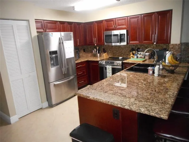 a kitchen with stainless steel appliances granite countertop a refrigerator a stove a sink and a microwave