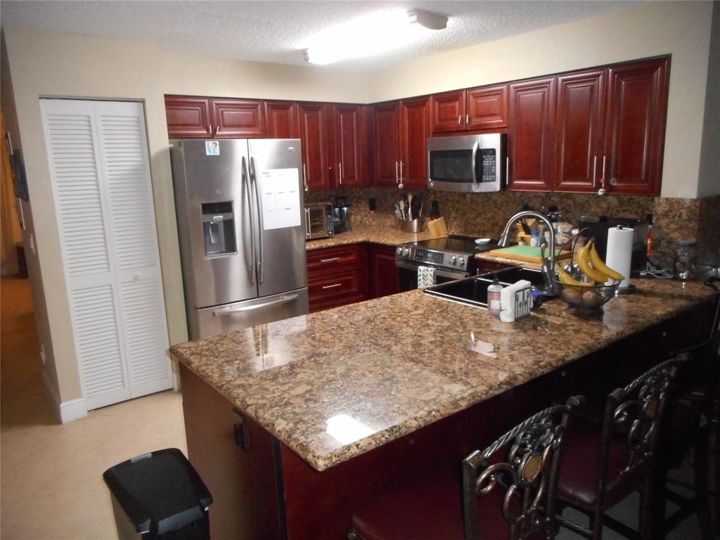 1741 Southwest 109th Terrace Davie, FL 33324 - Photo 7 of 10 a kitchen with granite countertop stainless steel appliances a stove top oven a refrigerator a sink and dishwasher